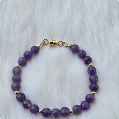 Amethyst bead bracelet with gold-filled beads and a gold-filled magnetic clasp, on white fur