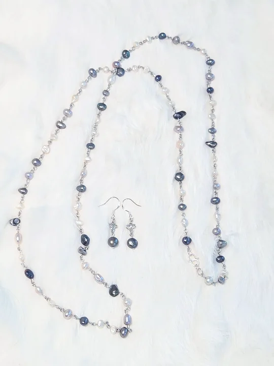 Long necklace of deep blue and white freshwater pearls linked with sterling silver, with matching earrings, on white fur