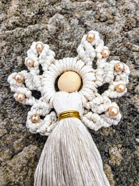 Cream macramé angel with pearls and gold beads, on a stone