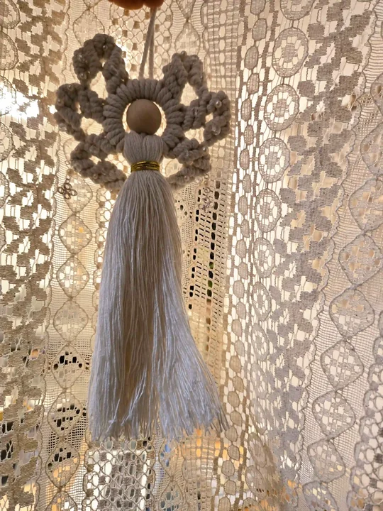 Dusty blue macramé angel in front of a lace curtain
