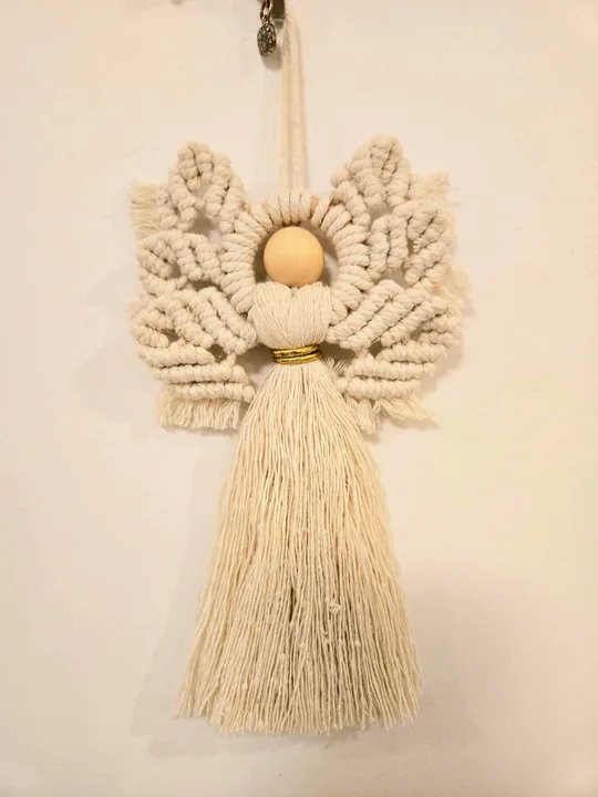Natural macramé angel with leaf-shaped wings on a white wall