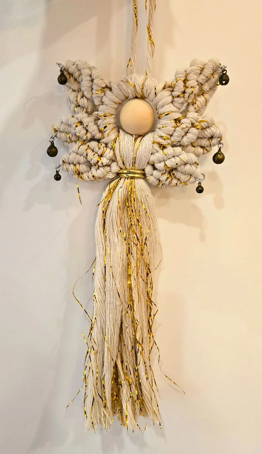 Cream macramé angel with gold threads in her skirt and little black bells