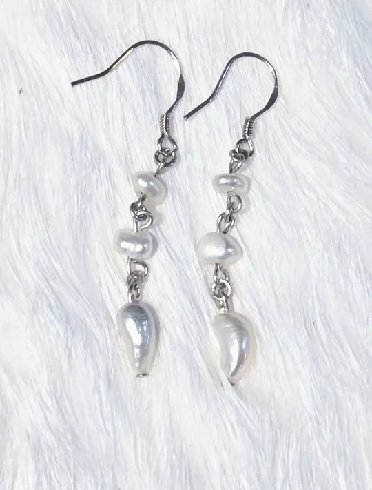 Asymmetrical dangle earrings of natural freshwater pearls and a shell drop, linked with 925 sterling silver, on white fur