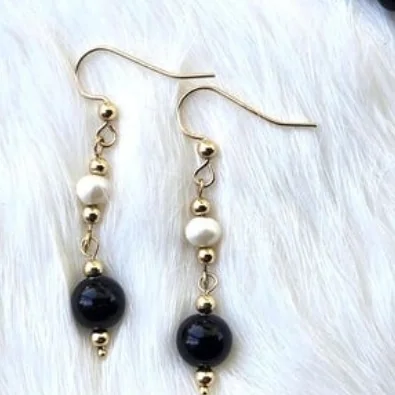 Dangle earrings with a black onyx bead, a white freshwater pearl and 14k gold-filled beads on gold ear hooks