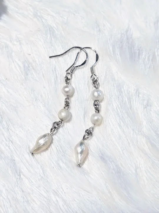 Dangle earrings of two round white natural freshwater pearls and a shell drop, linked with 925 sterling silver, on white fur